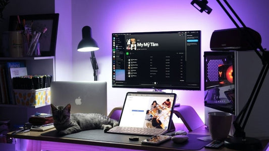 Minimalist desk setup featuring a clean white workspace with a pastel keyboard, wireless mouse, cat, and soft lighting